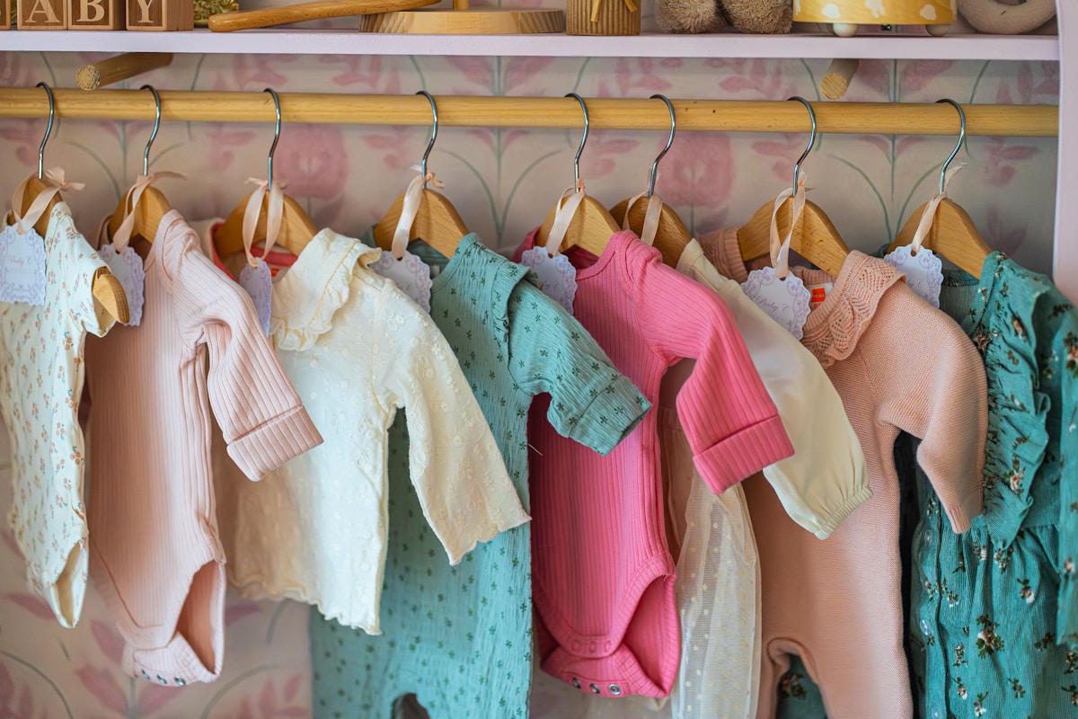 Colorful baby clothes hanging neatly on a wardrobe rail